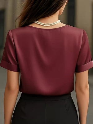 Wine red satin shirt with cuffed sleeves and V-neck, styled with a pearl necklace.