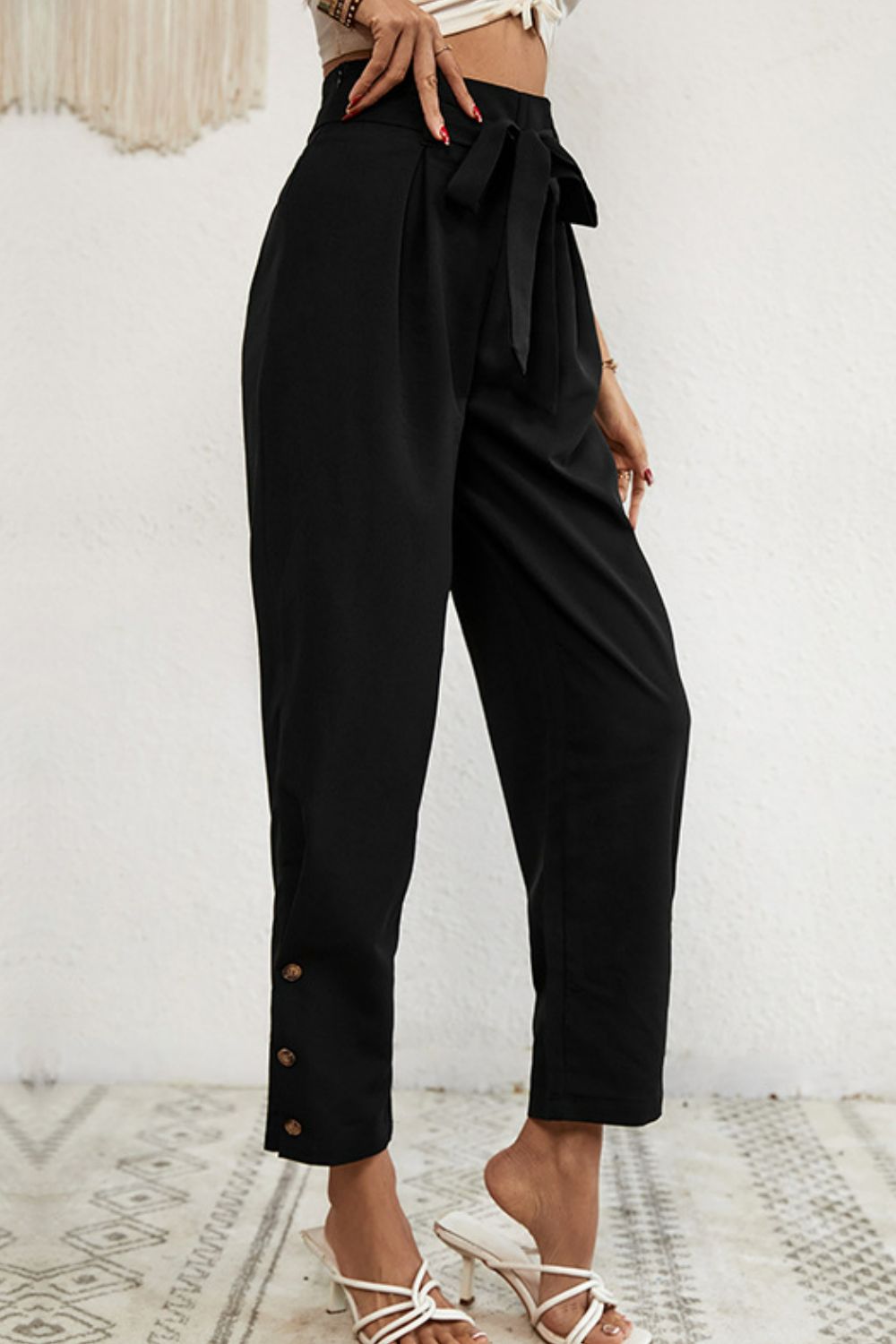 Black paperbag waist trousers with buttoned hemline and tie belt.