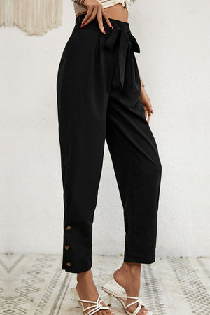 Black paperbag waist trousers with buttoned hemline and tie belt.