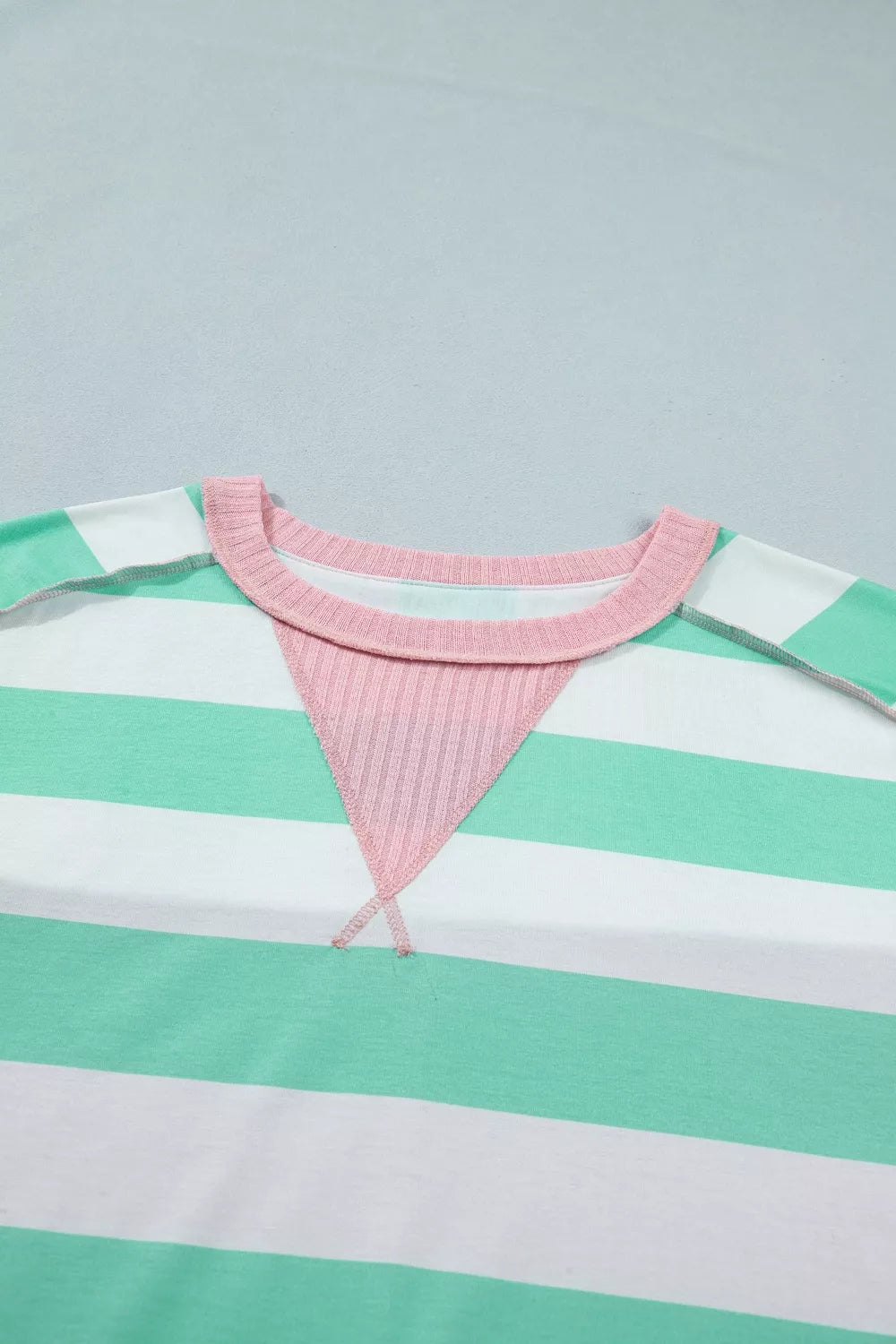 Oversized t-shirt with green and white stripes, pink ribbed neckline and triangular detail.