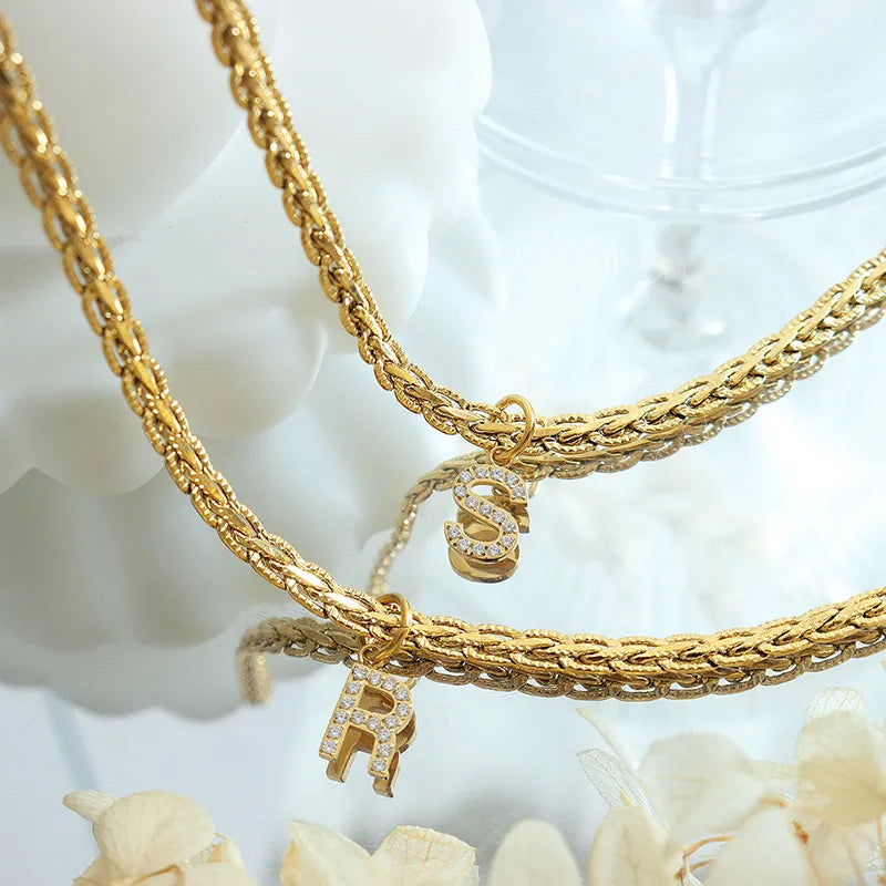 Gold textured chain necklace with initial charms R and S, detailed with rhinestones.