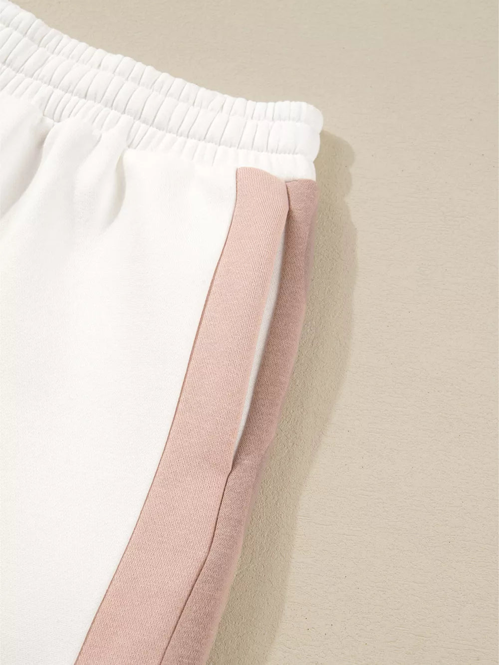White cotton pajama shorts with blush pink color block side stripe and elastic waistband.
