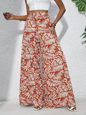 Orange-red palazzo trousers with a white tropical leaf print, made of 100% polyester.