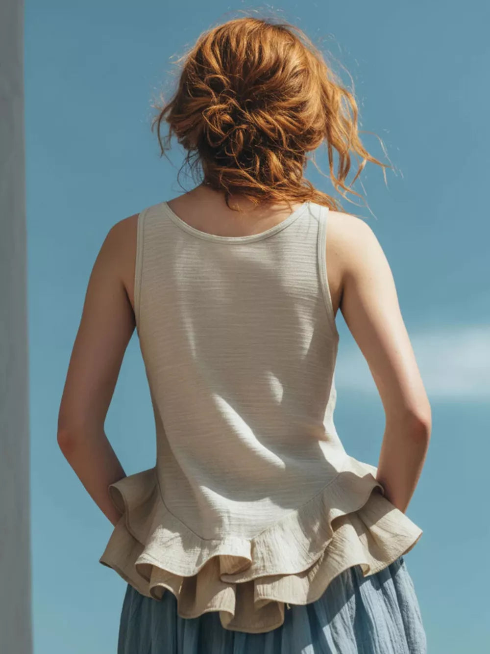 Off-white sleeveless tank top with a ruffled hem detail.