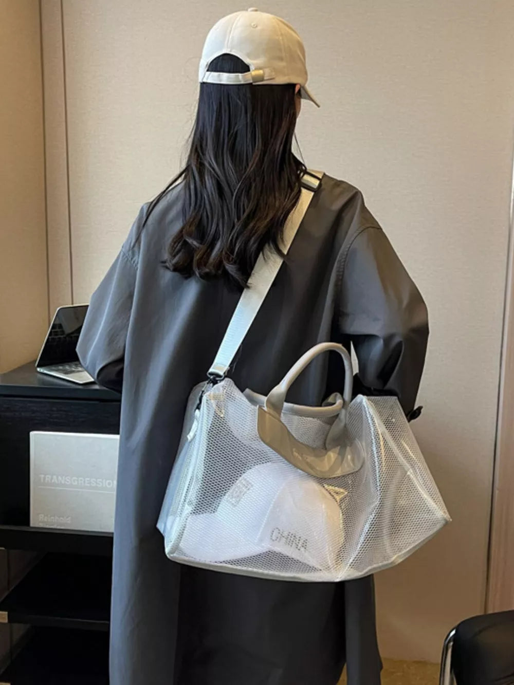 Light gray mesh travel organizer bag with clear PVC trim and handles, showing a white cap inside.