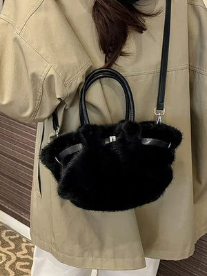 Plush crossbody bag in black with chic buckle detail and leather handles.