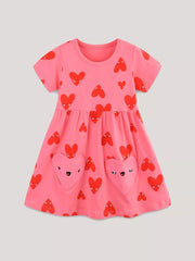 Pink cotton baby dress with red heart print and heart-shaped pockets.