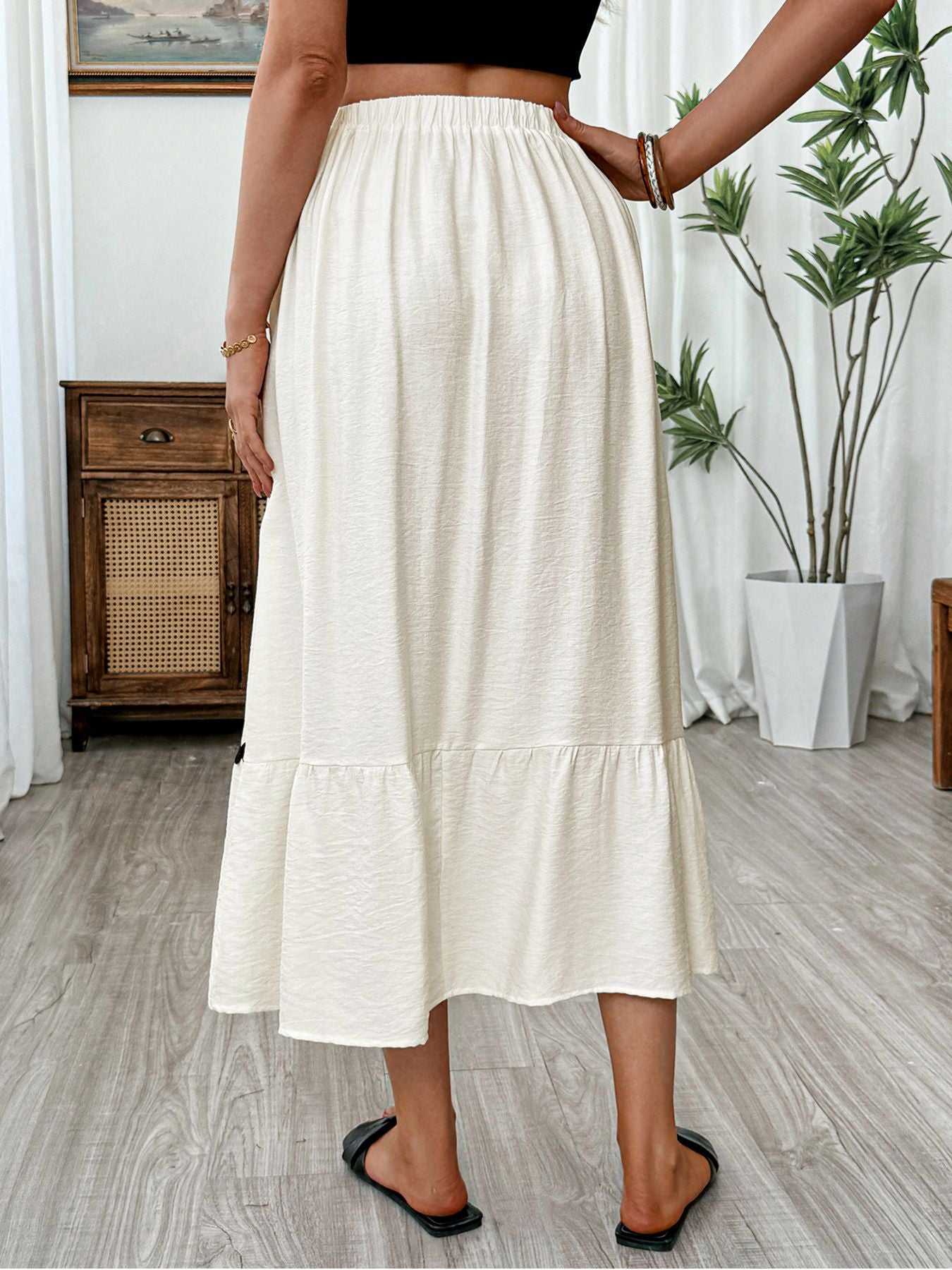 Elegant beige midi skirt with tiered hem and wavy trim, elastic waist, relaxed fit.