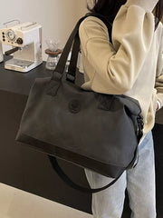 Black distressed duffle bag with adjustable strap and embossed logo detail.