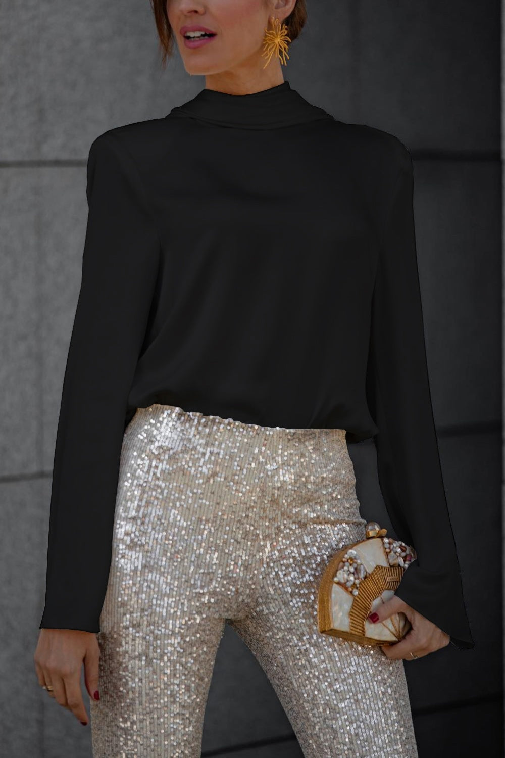Black silk blouse with high neck and draped back detail, paired with sequin pants.