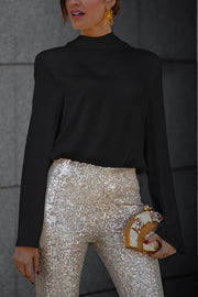 Black silk blouse with high neck and draped back detail, paired with sequin pants.