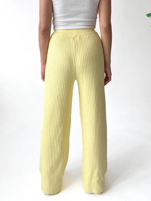 Luxe ribbed knit palazzo trousers in pastel yellow, featuring a wide leg and high waist.