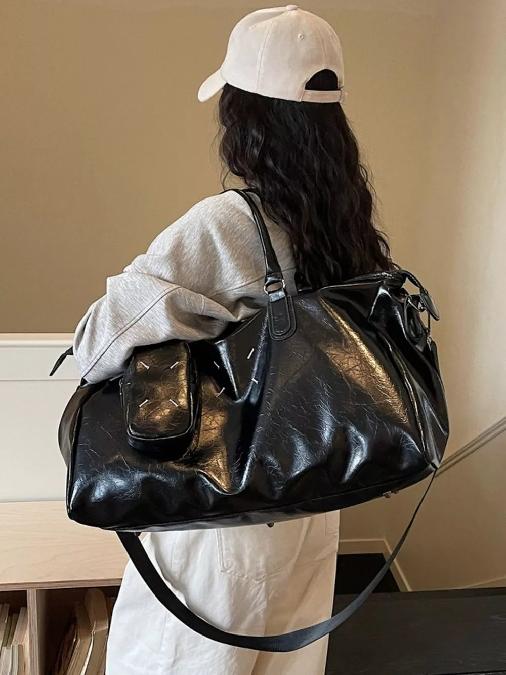 Black sleek metallic large travel bag with adjustable strap and front pocket detail.