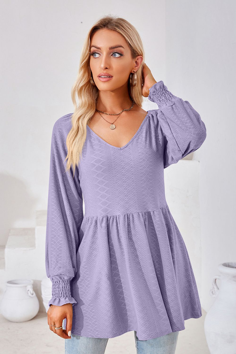 Lavender textured babydoll blouse with V-neck and smocked cuffs.