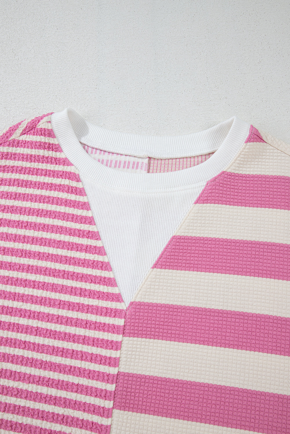 Pink and white striped waffle knit top with a white ribbed inset at the neckline.