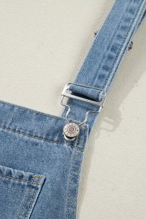 Denim wide-leg jumpsuit with buttoned straps and metal hardware detail.