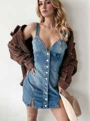 Medium wash denim button-down mini dress with V-neck, spaghetti straps, and side slits.