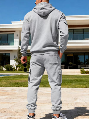 Men's light gray hooded sweatshirt and cargo sweatpants set with multiple pockets.