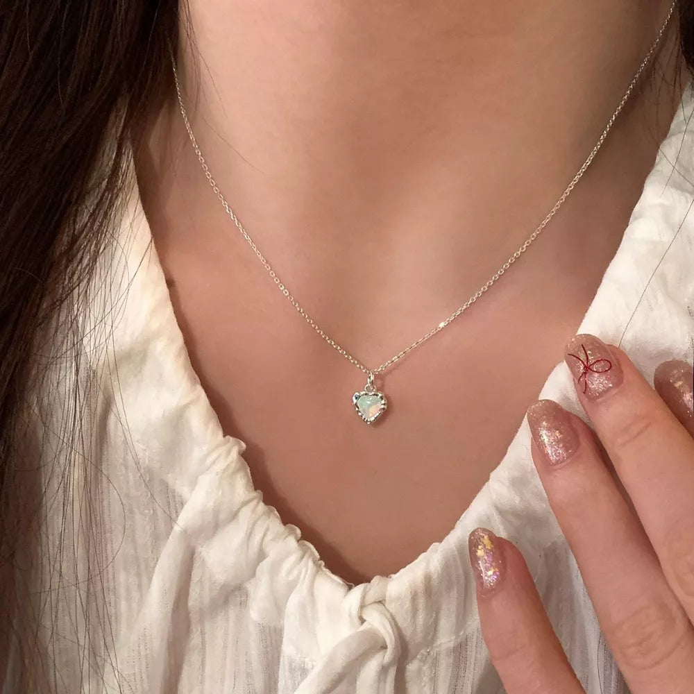 Dainty silver heart pendant necklace with opal detail on a delicate chain.