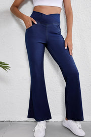 Medium wash denim flare trousers with a crossover waist and pockets.