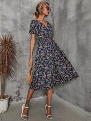 Dark blue midi dress with vibrant floral pattern, V-neck, short sleeves, and A-line skirt.