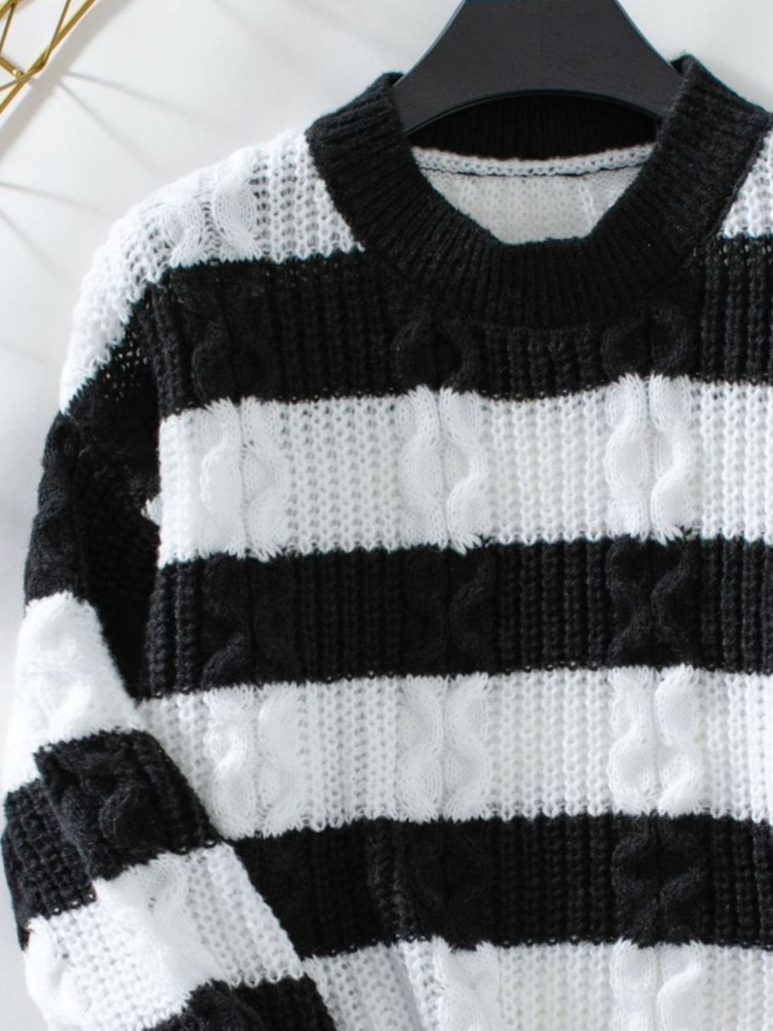 Black and white striped cable knit crewneck sweater with textured stitching.