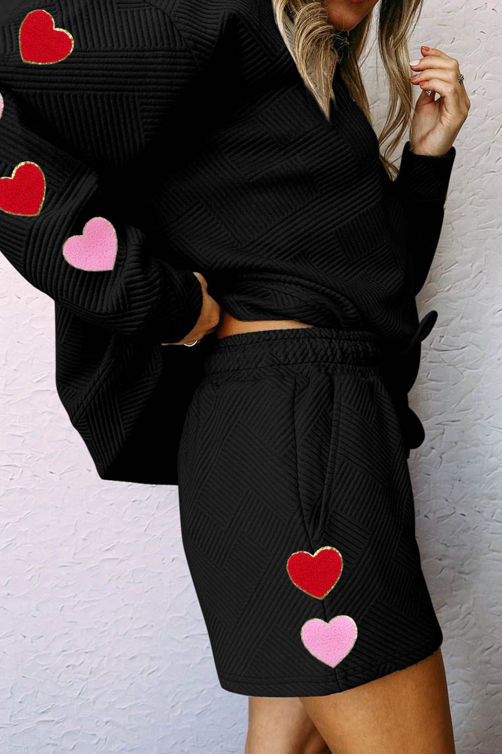 Black quilted lounge set with heart appliqués on sleeves and shorts.