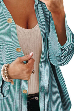 Turquoise striped overshirt with oversized fit and gold buttons, worn open over a cream tank top.