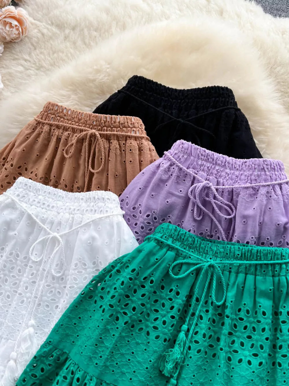 Delicate eyelet tiered maxi skirts in white, light brown, purple, green, and black with drawstring waists.