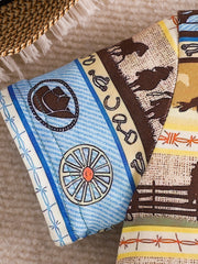 Children's western print tee with cowboy hat, wagon wheel, horses, and fence details.