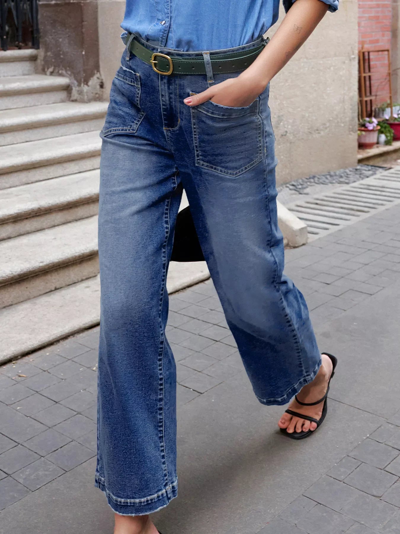 Patch pocket wide-leg jeans in medium wash denim with a green belt.