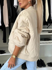 Beige quilted bomber jacket with rounded sleeves and ribbed cuffs.