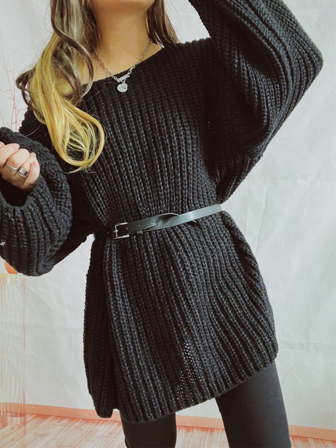 Black oversized ribbed knit sweater with belted waist and wide sleeves.