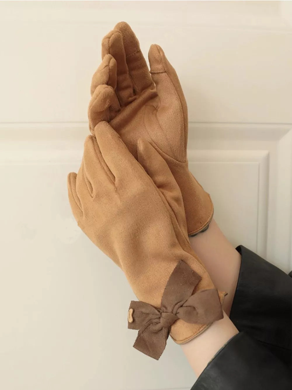 Camel suede gloves with brown bow detail and button accent.