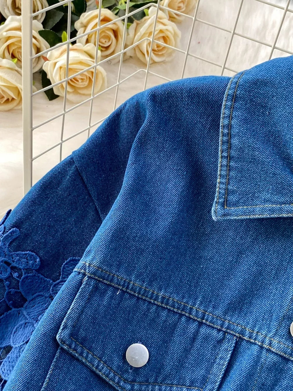 Blue denim jacket with lace sleeves and button-up front.