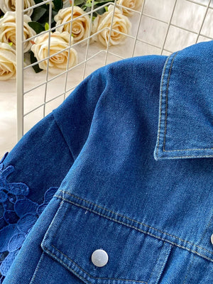 Blue denim jacket with lace sleeves and button-up front.