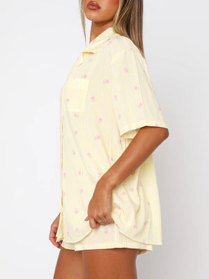 Pastel yellow striped pajama set with pink floral print, collared button-up shirt and shorts.