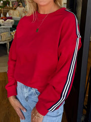 Red sweatshirt with varsity stripe detail on sleeves.
