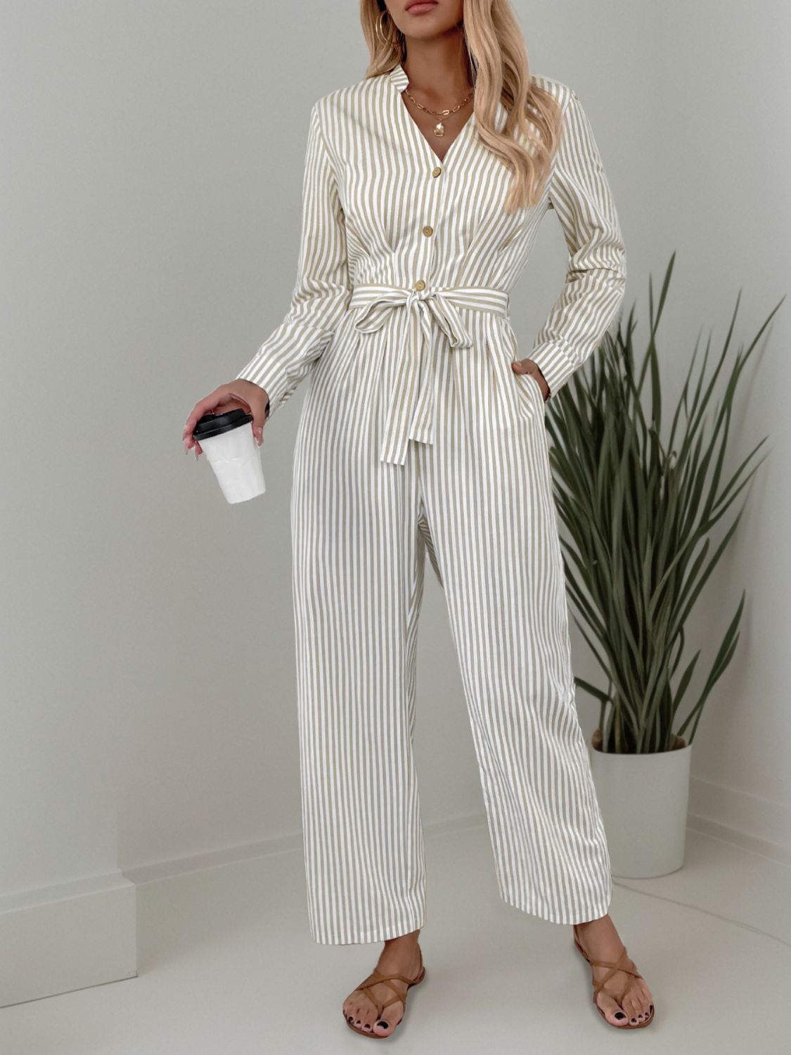 Beige vertical stripe button-down jumpsuit with tie waist and wide legs.