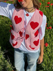 Quilted blush pink vest with red heart appliqué and tie closure, worn over a white tee.