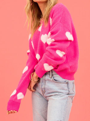 Fuchsia pink crewneck sweater with white intarsia hearts, crew neck, long sleeves.