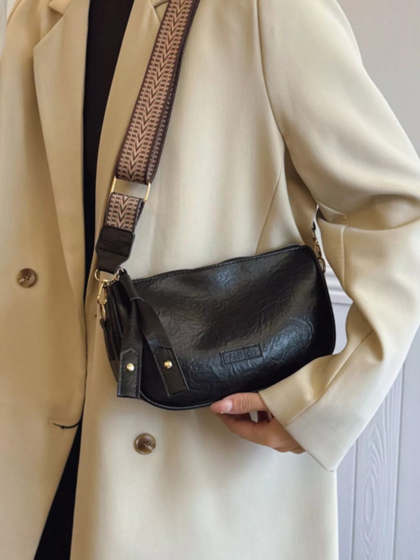 Black crossbody bag with textured faux leather and patterned strap