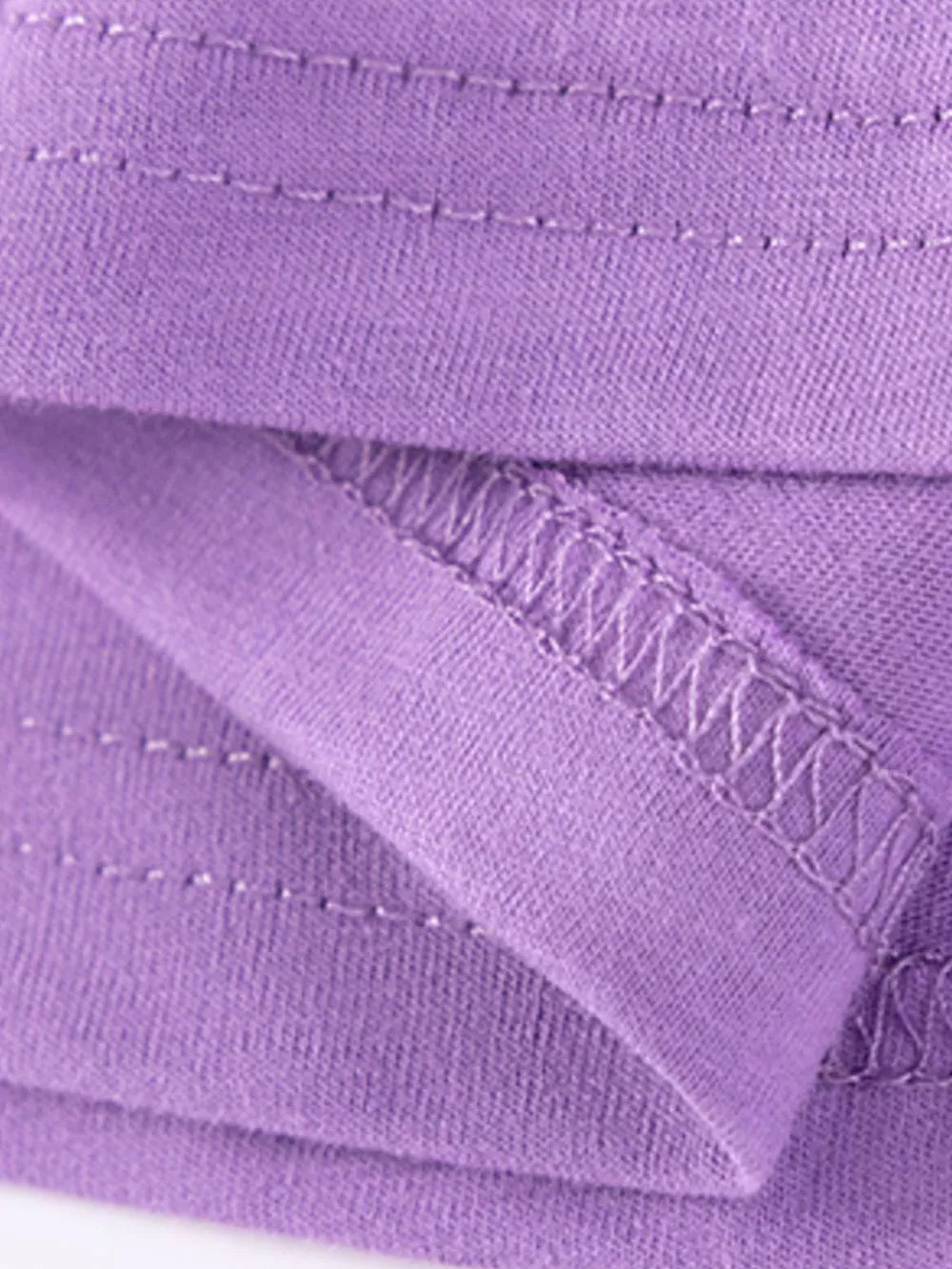 Purple cotton toddler dress detail showing stitching and fabric texture.