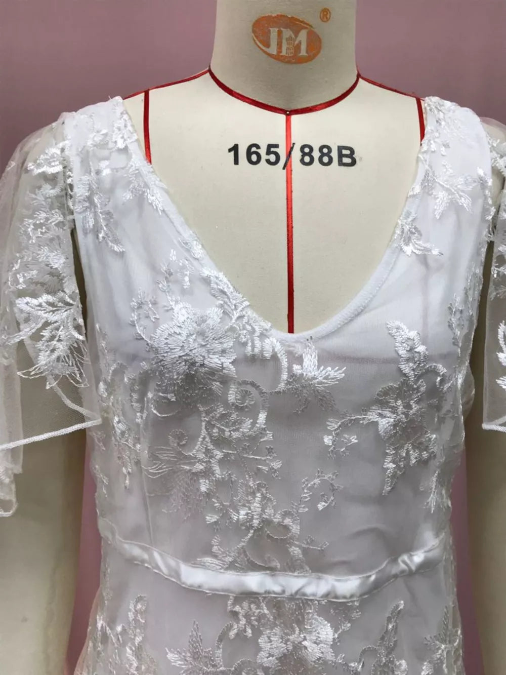 White lace v-neck dress with flutter sleeves and floral embroidery.