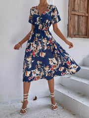 Blue midi dress with vibrant leaf pattern, V-neck, short sleeves, and smocked waist.
