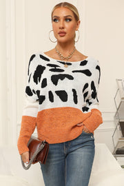 Cow print off-shoulder knit sweater with orange colorblock detail and boat neck.