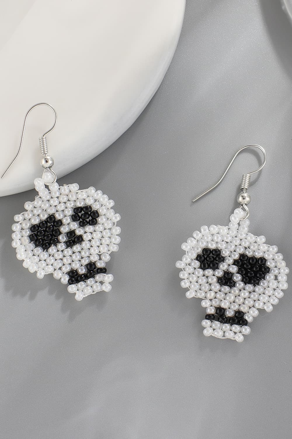 Beaded skull earrings in white with black accents.