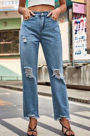 Distressed hem straight leg jeans in medium wash denim with ripped knees and frayed hems.