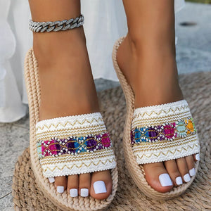 Embossed strap open-toe flat sandals with colorful embroidered detail and braided sole.