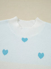 Light blue and white knit sweater with a playful heart pattern and crew neck.
